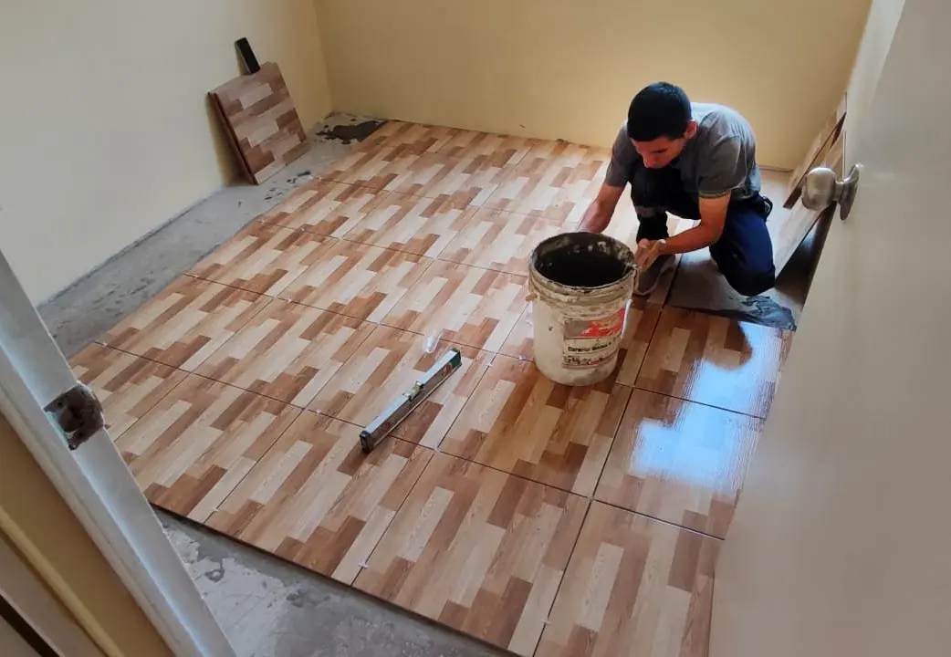 Instalador de mayolica colocando piso tipo madera - Servicio de Cerámica y Porcelanato en Lima